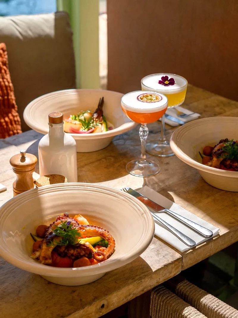 Poulpe grillé et deux cocktails à la passion sur une table en bois