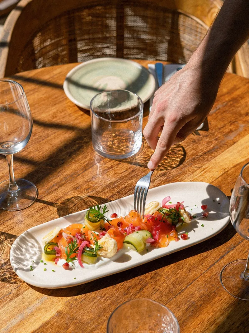 Assiette de saumon, concombre et grenade servie en terrasse